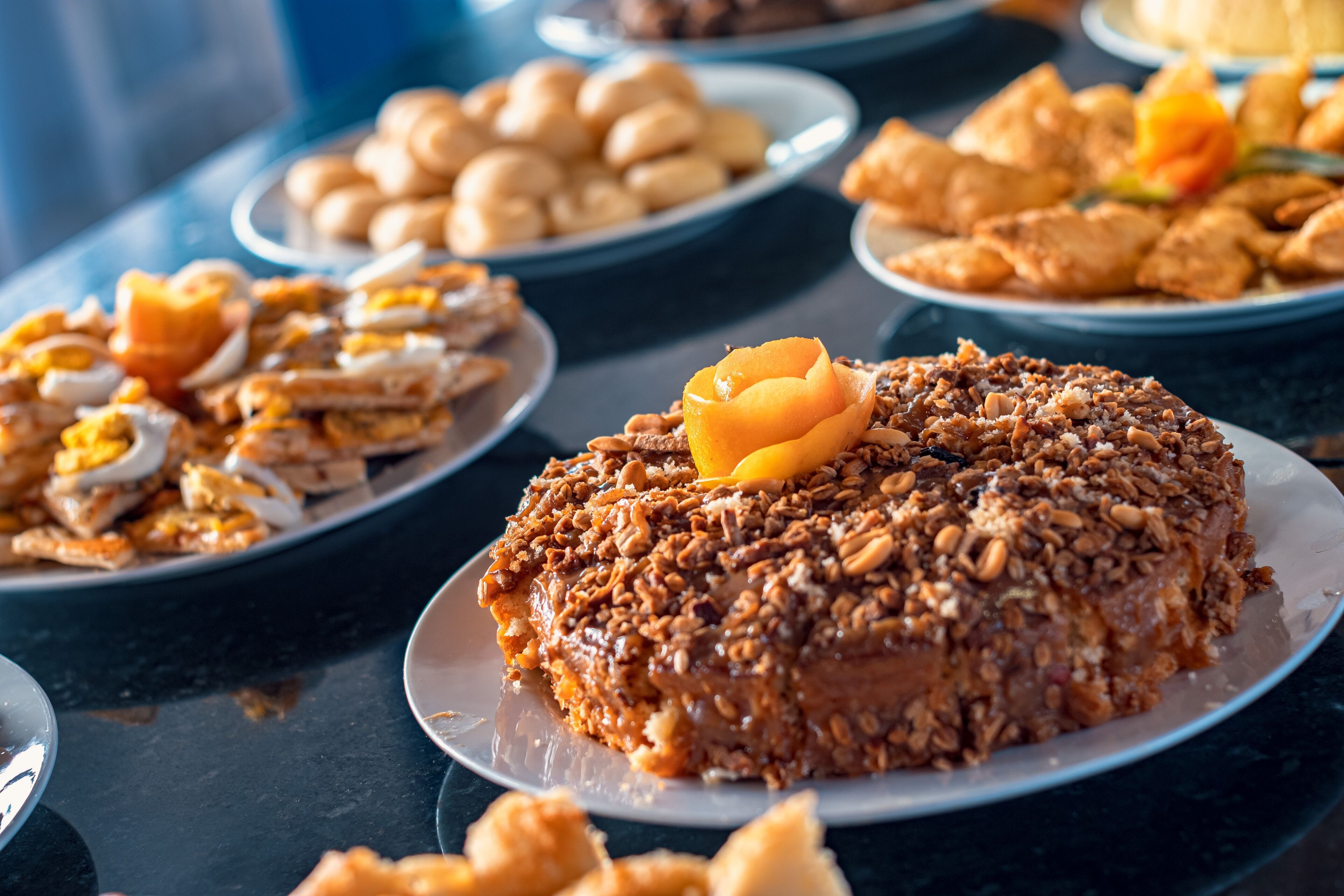 A variety of dishes on plates, including a cake with nuts and a flower on top.