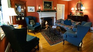 A living room with a fireplace, two sofas, a coffee table, and a patterned rug. - Inn at Monticello (Charlottesville)