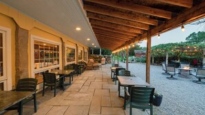 An outdoor patio with stone flooring, wooden beams, and tables and chairs. - Stonecroft Inn (Ledyard)