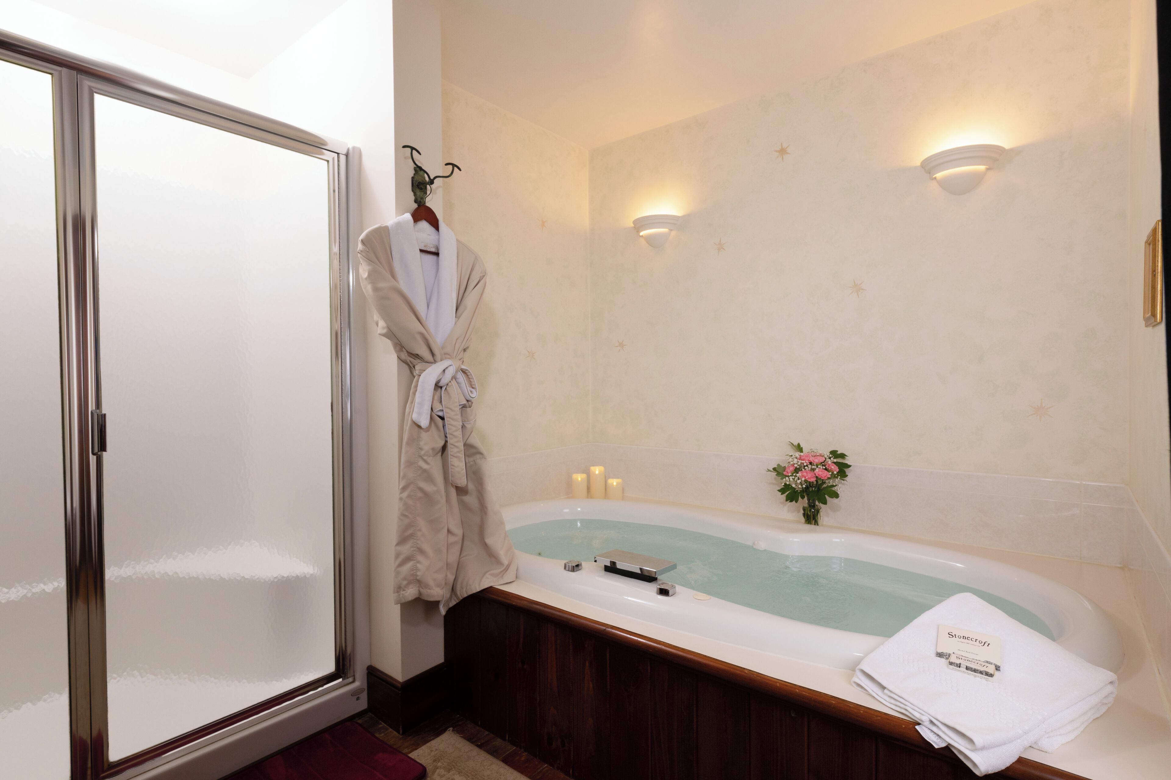 A bathroom with a bathtub, a robe hanging on a rack, and a towel on the edge of the tub.