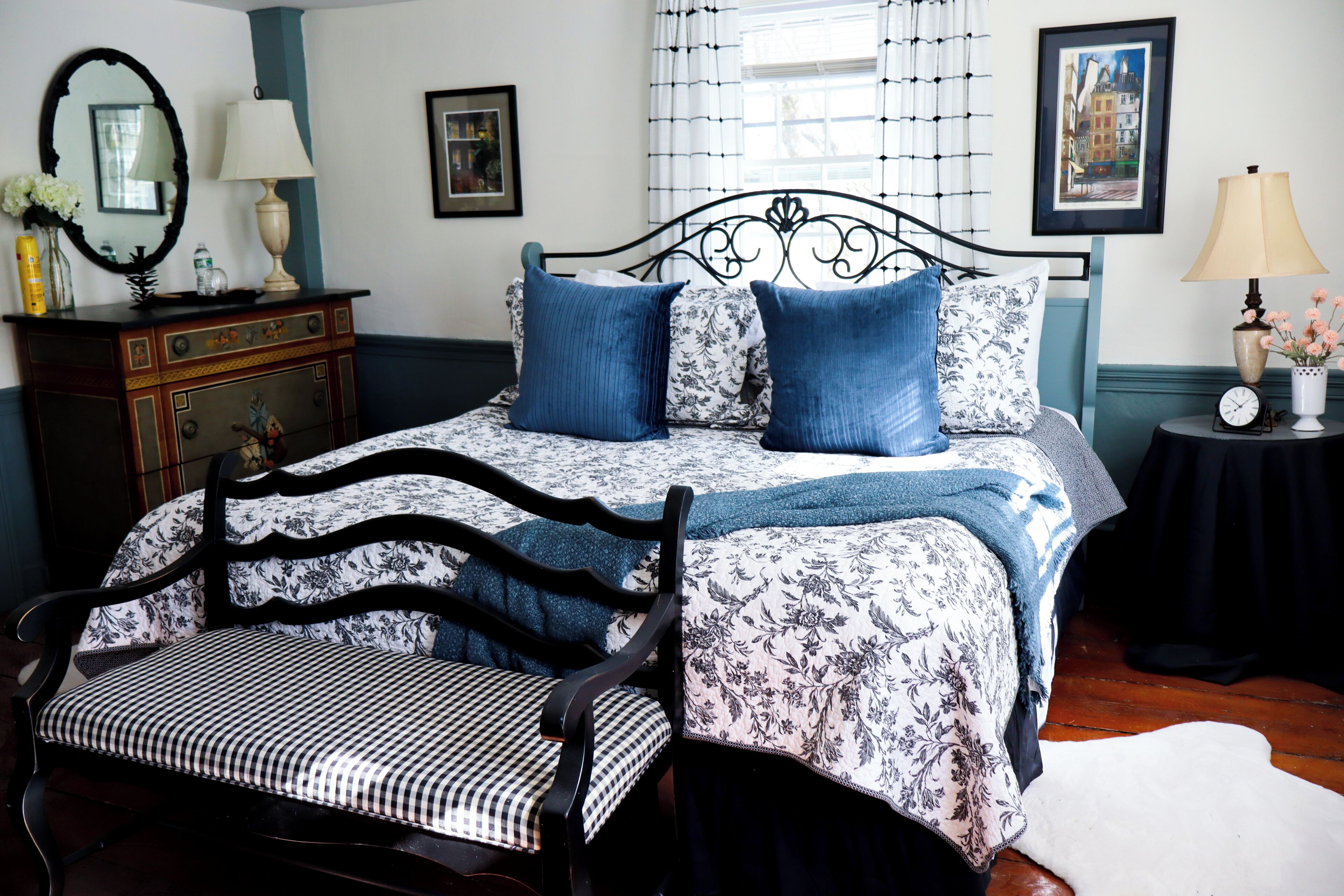 A bedroom with a bed, a chair, a dresser, a mirror, and a picture on the wall.