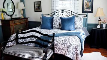 A bedroom with a bed, a chair, a dresser, a mirror, and a picture on the wall.