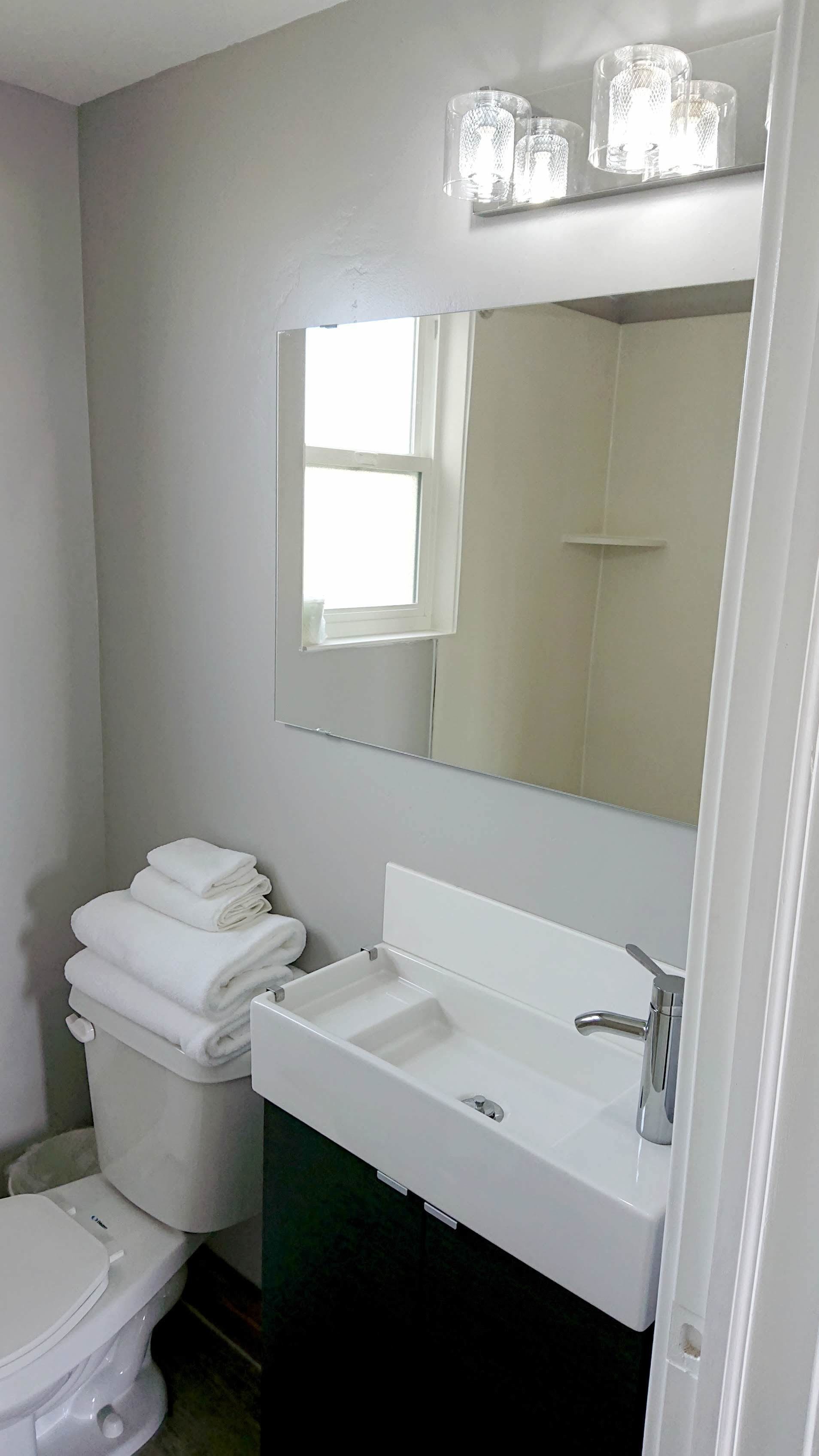 A bathroom with a white sink, a mirror, and a toilet.