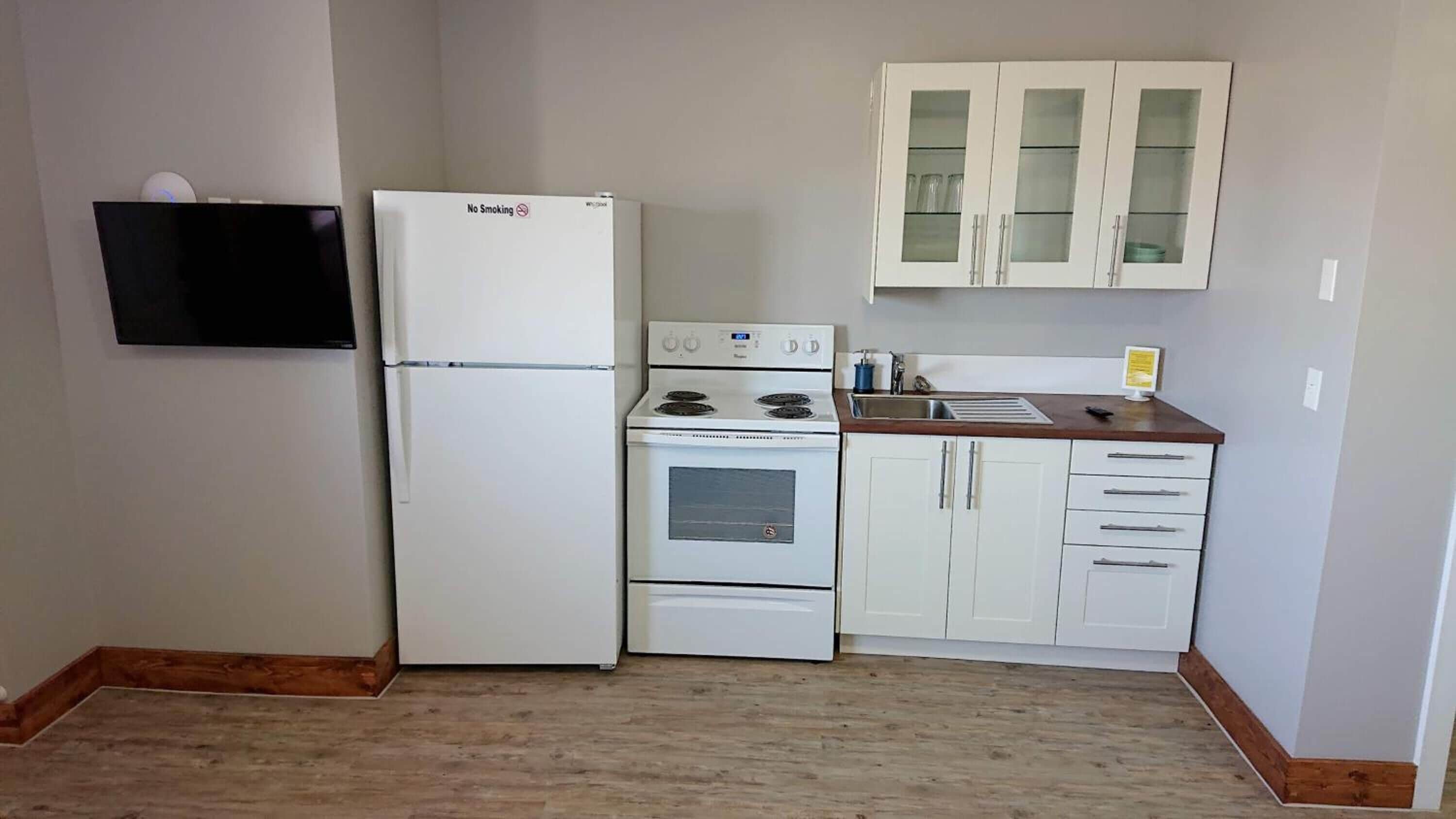 A compact kitchen with a refrigerator, stove, and cabinets.