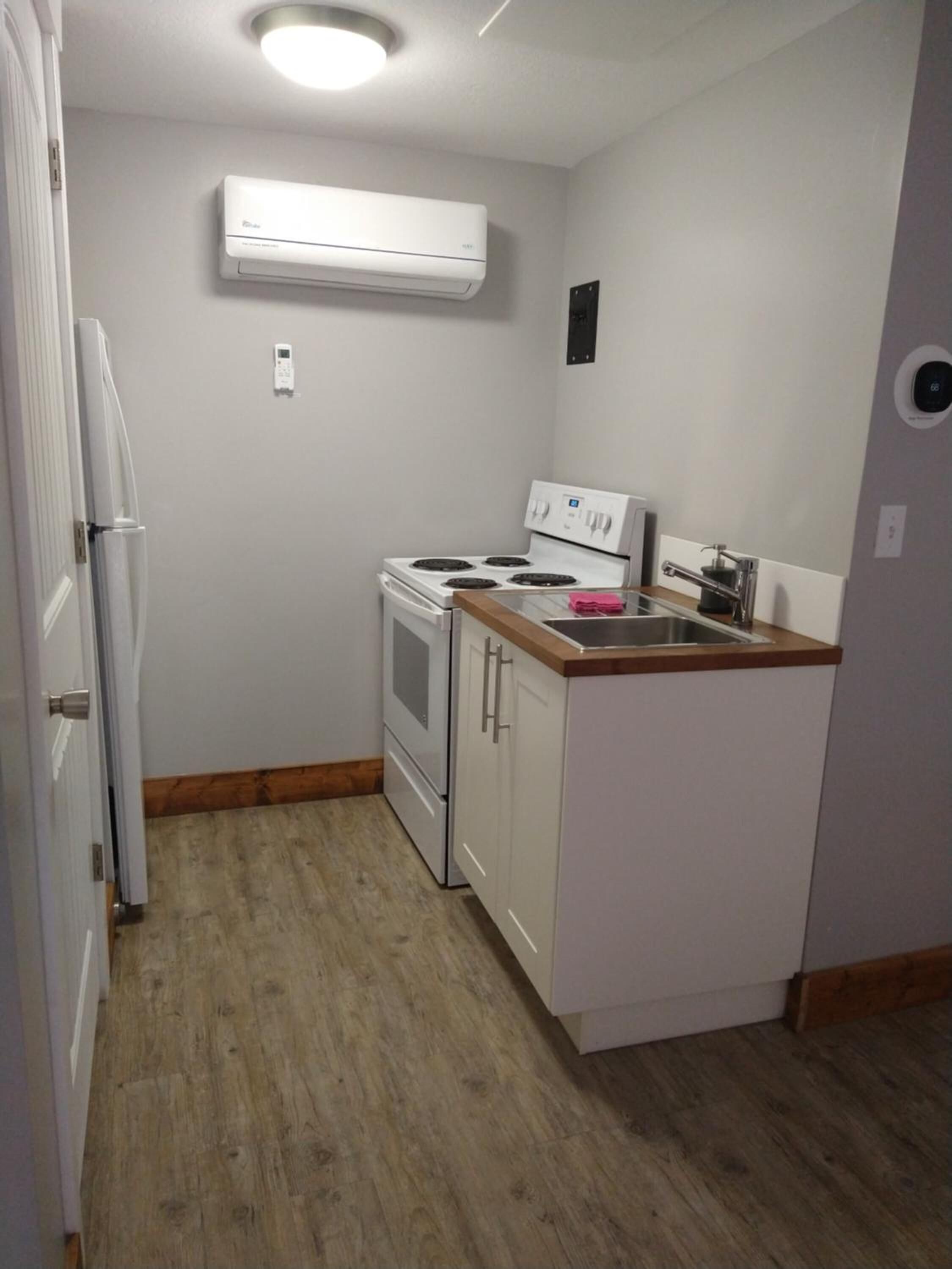 Una cocina compacta con muebles blancos, horno integrado, estufa y una pequeña encimera.