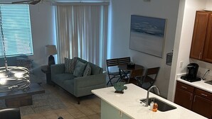 A modern kitchen with a central island, a dining area with a table and chairs, a living room with a sofa and a TV, and a staircase leading to another level. - BEAUTIFUL LAKEVIEW TOWNHOME, 5 MILES TO DISNEY... FULLY EQUIPED (kissimmee)