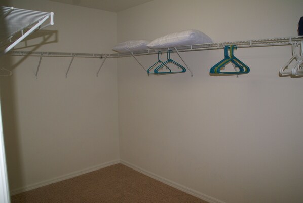 A laundry area with a metal rack, two blue hangers, and a white pillow.