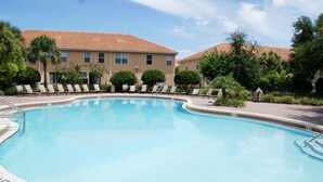 A swimming pool with lounge chairs and palm trees, surrounded by a building with a tiled roof. - BEAUTIFUL LAKEVIEW TOWNHOME, 5 MILES TO DISNEY... FULLY EQUIPED (kissimmee)