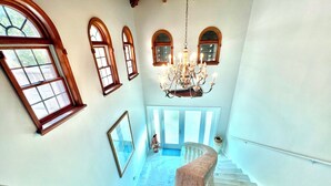 A grand staircase with marble steps leading up to a landing with a chandelier and arched windows. -  “RENOVATED Gorgeous House with ocean views from balconies, with Hot Tub & Pool” (Marathon)