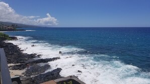A coastal view with rocky shoreline, ocean waves, and a clear sky.