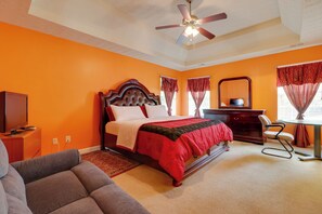 Une chambre à coucher comprenant un lit, un bureau, une chaise, un téléviseur et un ventilateur de plafond.