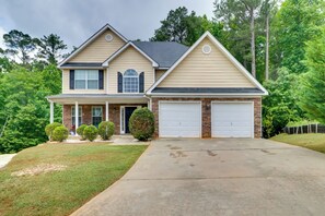 A two-story house with a front porch, a garage, and a well-maintained lawn. - Suburban Atlanta Vacation Home - 20 Mi to Downtown (Atlanta)