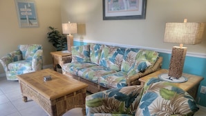 A living room with a sofa, two armchairs, a coffee table, and two floor lamps.