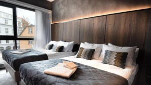 Een hotelkamer met twee bedden, een groot raam en uitzicht op gebouwen.