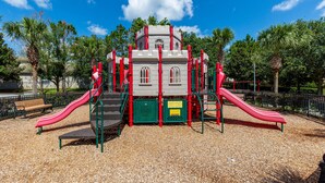 Une aire de jeux avec deux toboggans, une structure d’escalade et un banc.