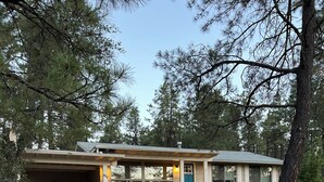 Ein eingeschossiges Gebäude mit Garageneinfahrt, überdachter Veranda und grüner Tür.