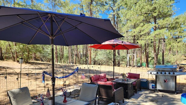 Eine überdachte Terrasse im Freien mit Tischen, Stühlen und einem Grill.