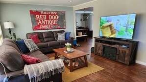 Ein Wohnzimmer mit einem braunen Ledersofa, einem Couchtisch, einem Fernseher auf einem Holzgestell und einem roten Schild an der Wand.