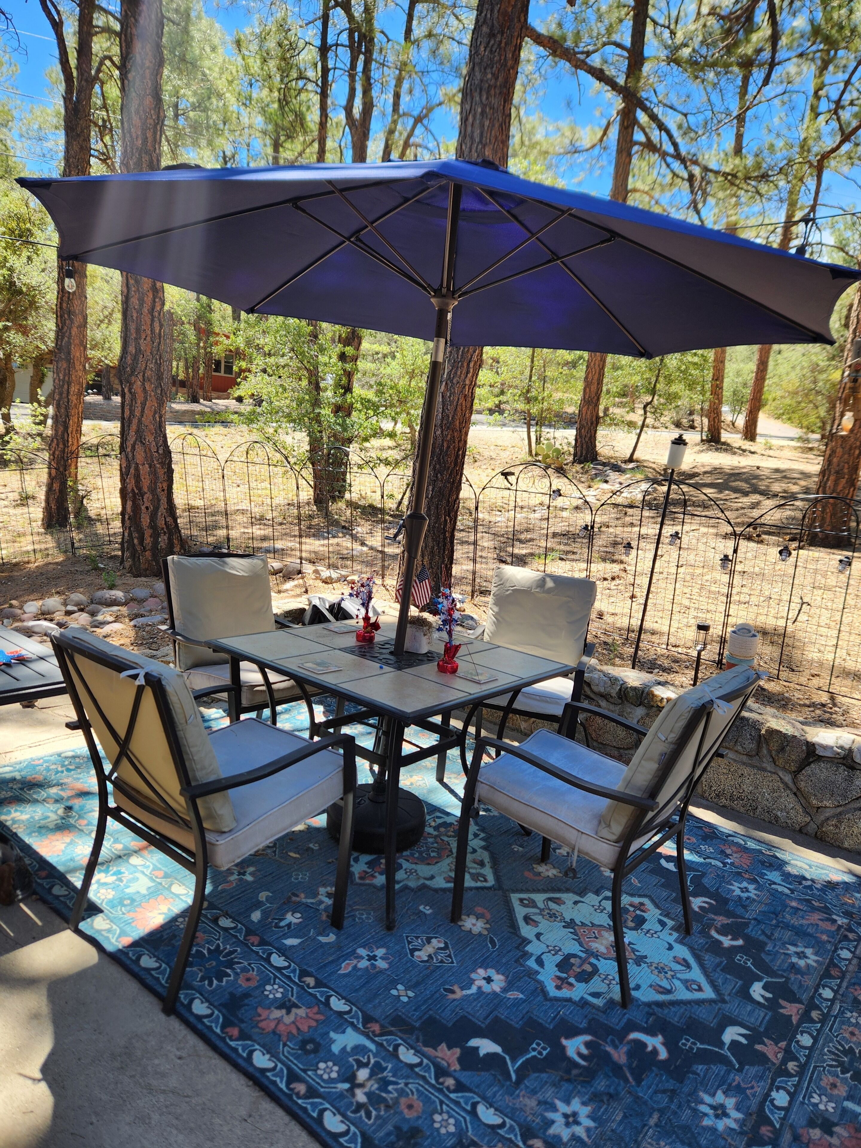 An outdoor patio with a table and chairs, surrounded by trees.
