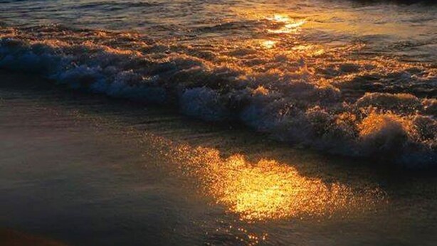 A sunset over the ocean with waves.
