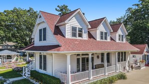 A two-story house with a red roof, white siding, and a covered porch.