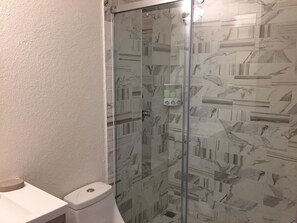 Bathroom features a glass shower enclosure and a toilet, with a minimalist design.