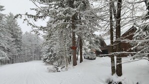 Eine schneebedeckte Straße mit einem geparkten Fahrzeug neben einem Gebäude.