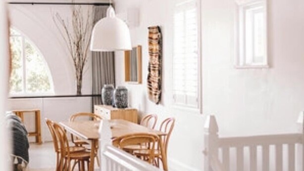 A modern interior with a dining area, white railing, and a staircase. - Flourish ON Bull - Stunning New Loft Apartment - Iconic Building  (Newcastle)