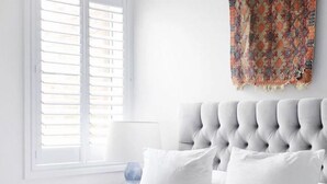 A bedroom with a tufted headboard, white bedding, and a patterned throw on the wall. - Flourish ON Bull - Stunning New Loft Apartment - Iconic Building  (Newcastle)
