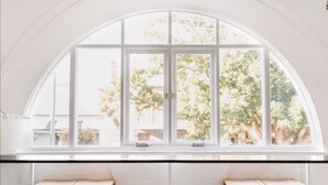A large arched window with a view of trees and a building outside. - Flourish ON Bull - Stunning New Loft Apartment - Iconic Building  (Newcastle)