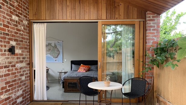 A cozy room with a bed, a map on the wall, and a small table with chairs. - Inner city garden studio in the heart of Footscray (Footscray)