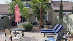 A patio with outdoor furniture, a palm tree, and a building in the background.