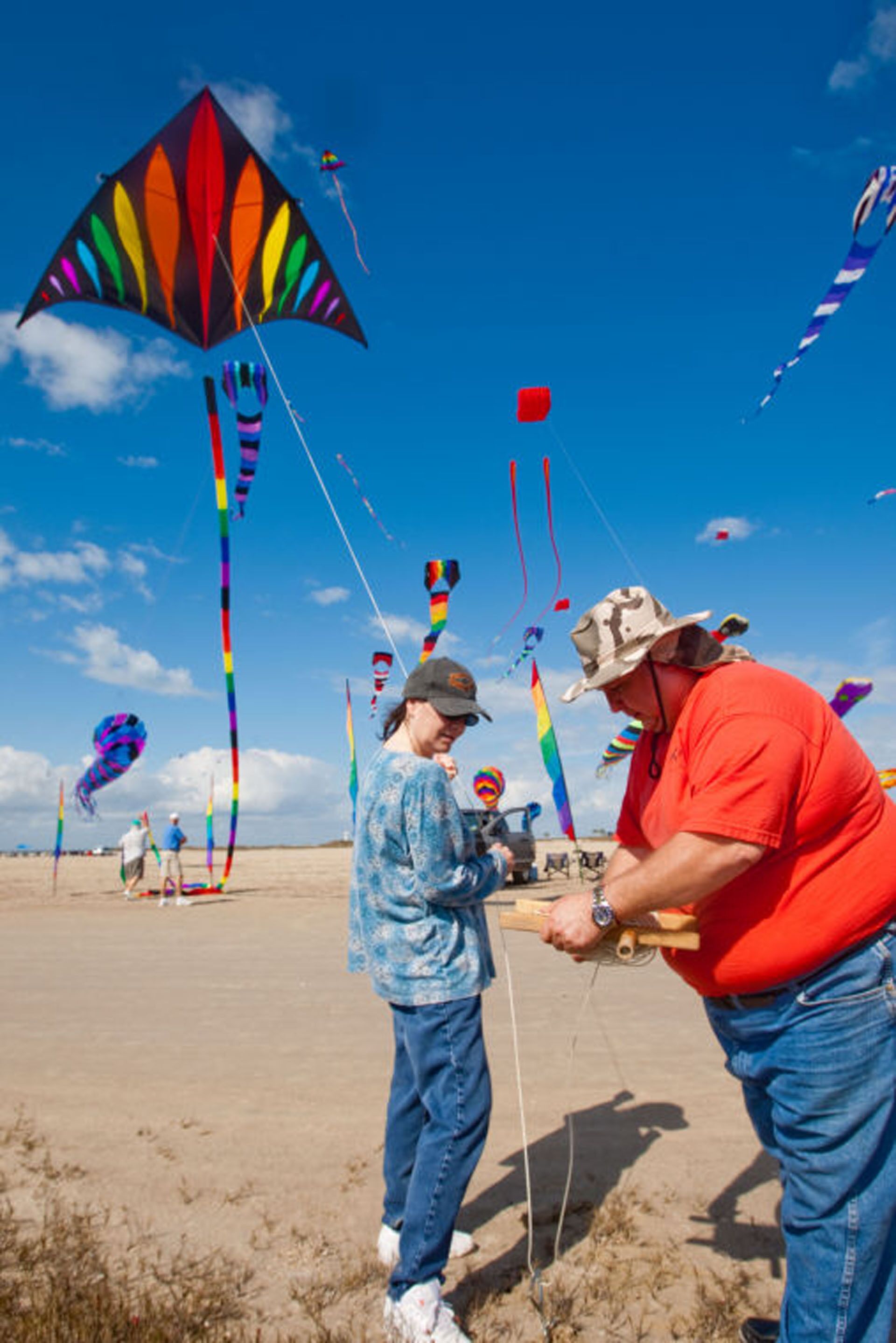 A beach scene with people flying kites.