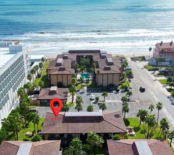 A hotel with a central courtyard, surrounded by buildings and a view of the ocean.