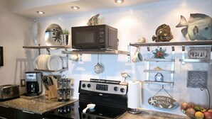 Una cucina con fornello, forno a microonde, tostapane e diversi utensili da cucina.