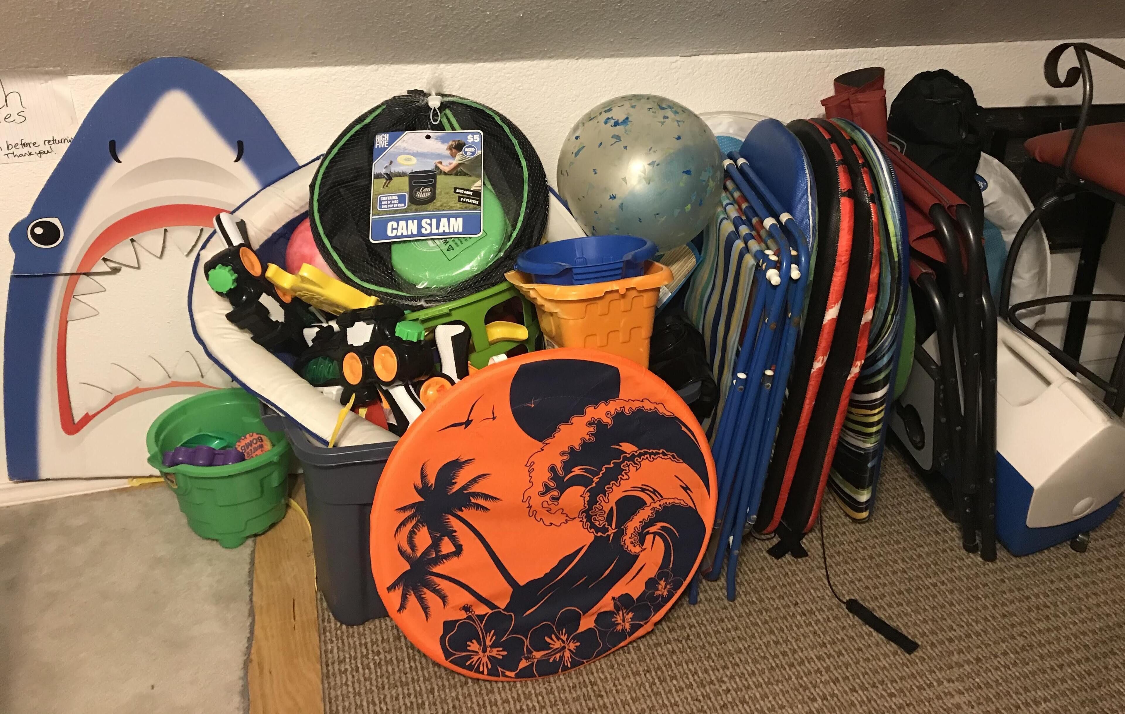 A collection of beach toys, including a shark-shaped board, a can slammer, and a surfboard.