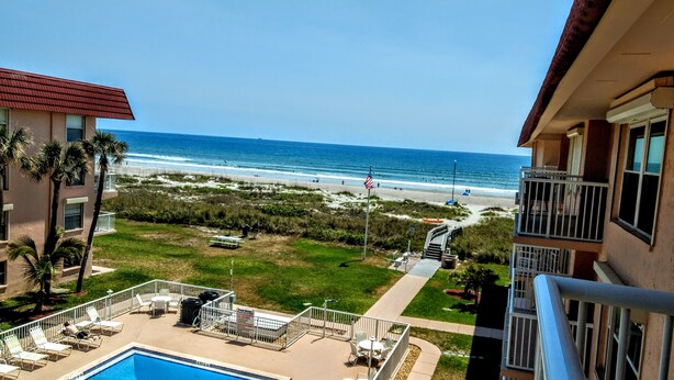 A hotel with a pool, a view of the beach, and a flag.
