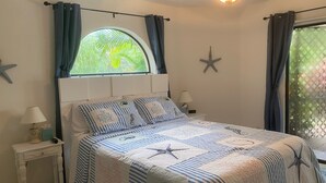 Ein Schlafzimmer mit Bett, Nachttisch, einem Fenster mit Vorhängen, Deckenventilator und Sternen an der Wand.