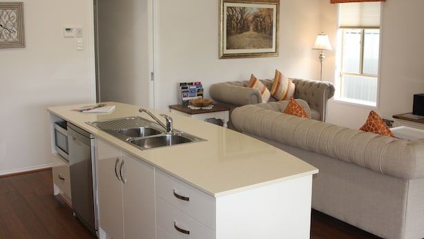 A modern kitchen with a built-in sink and a dining area with a sofa and cushions. - C and C Tanunda (Tanunda)