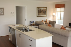 A modern kitchen with a built-in sink and a dining area with a sofa and cushions.
