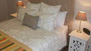 A neatly made bed with a patterned bedspread, two bedside lamps, and a clock on the nightstand. - C and C Tanunda (Tanunda)