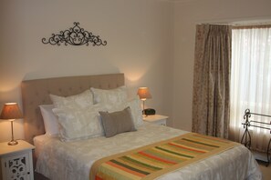 A neatly made bed with a striped blanket, two bedside lamps, and a wall-mounted decorative piece.