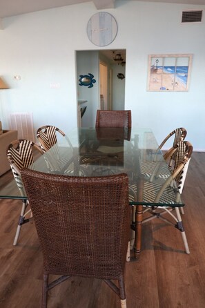 A dining area with a glass-top table surrounded by wicker chairs.