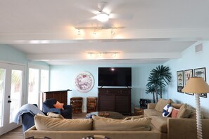 A living room with a sofa, a television, and a ceiling fan.