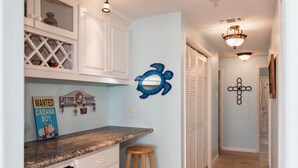 A kitchen with white cabinets, a granite countertop, a wooden stool, and a 'Wanted' sign. - On The Bay In Sea Isle: Fishing, Family, Fun! (Galveston)
