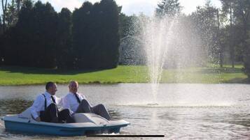 Two people in a boat on a lake with a fountain in the background.