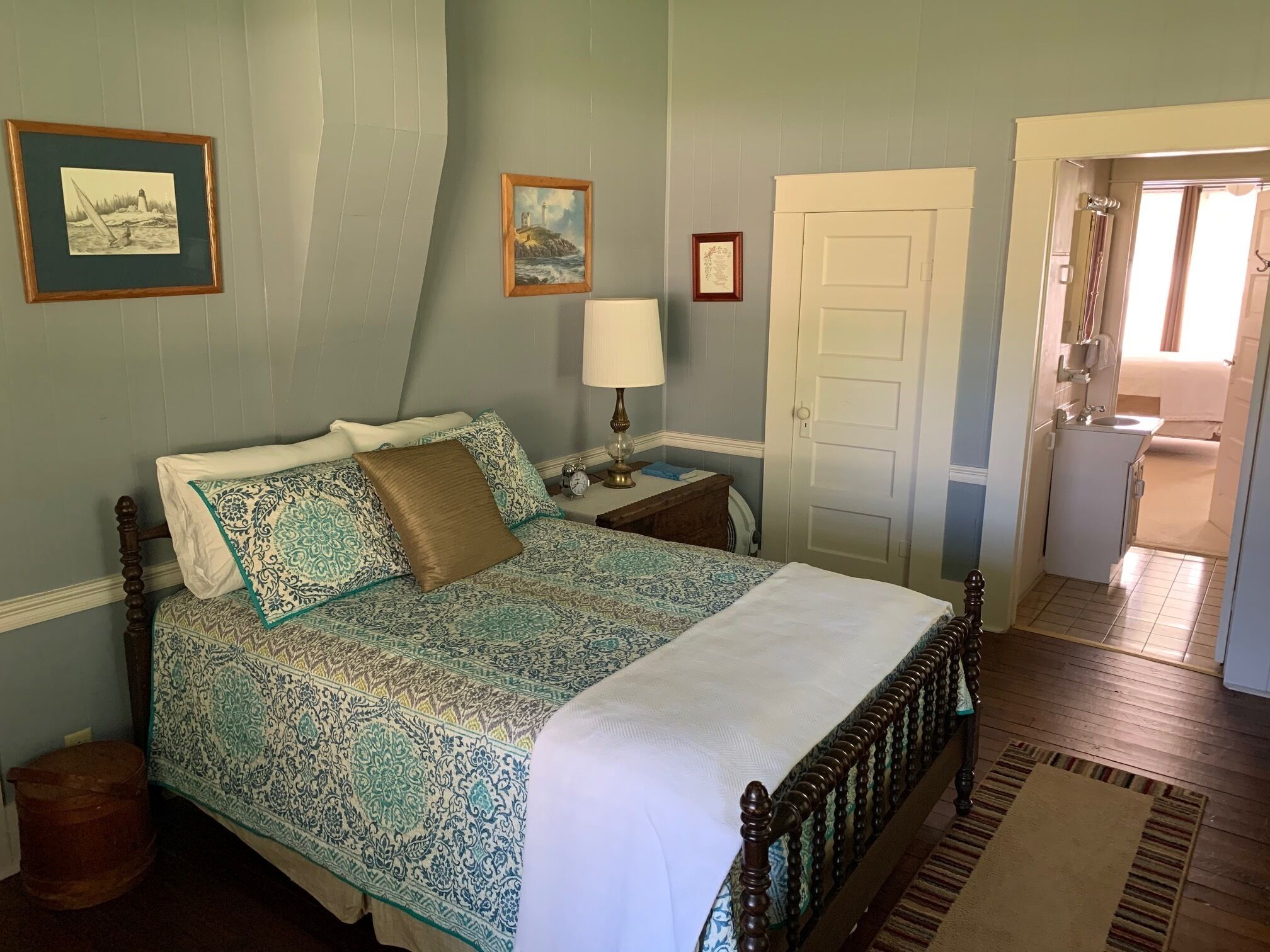 A bedroom with a bed, a nightstand, a lamp, and two framed pictures on the wall.
