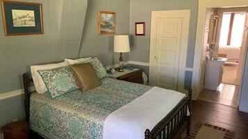 A bedroom with a bed, a nightstand, a lamp, and two framed pictures on the wall.