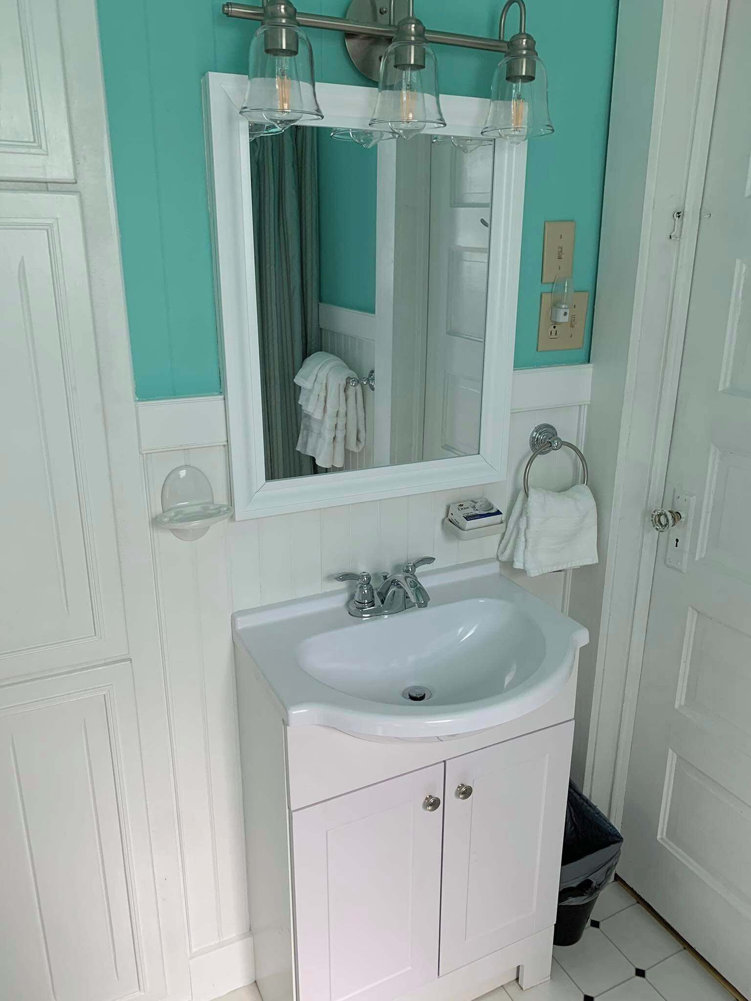 Une salle de bain avec un lavabo blanc, un miroir et un porte-serviettes.