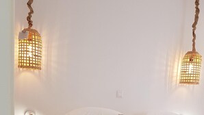 Un dormitorio minimalista con una cama, un taburete pequeño y dos lámparas de pared.